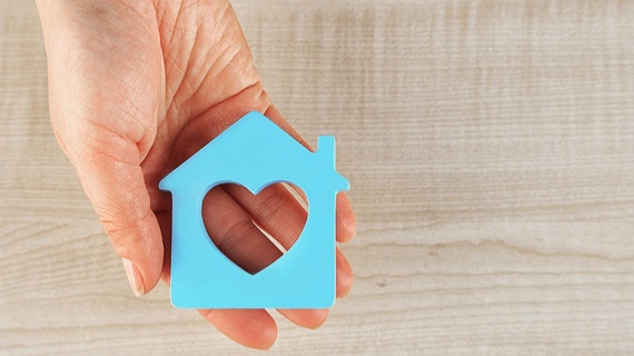 hand-holding-blue-wooden-house-representing-care-home-safety.jpg.jpg