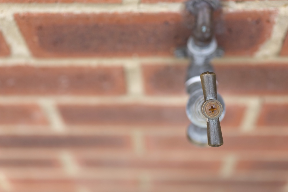 Detail of outside tap on a red brick wall.jpeg